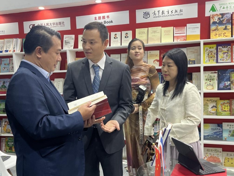 泰國書商和出版商協(xié)會主席蘇維奇（左一）在翻閱《近鏡頭：溫暖的瞬間》。（盧雯 攝）jpg_副本.jpg